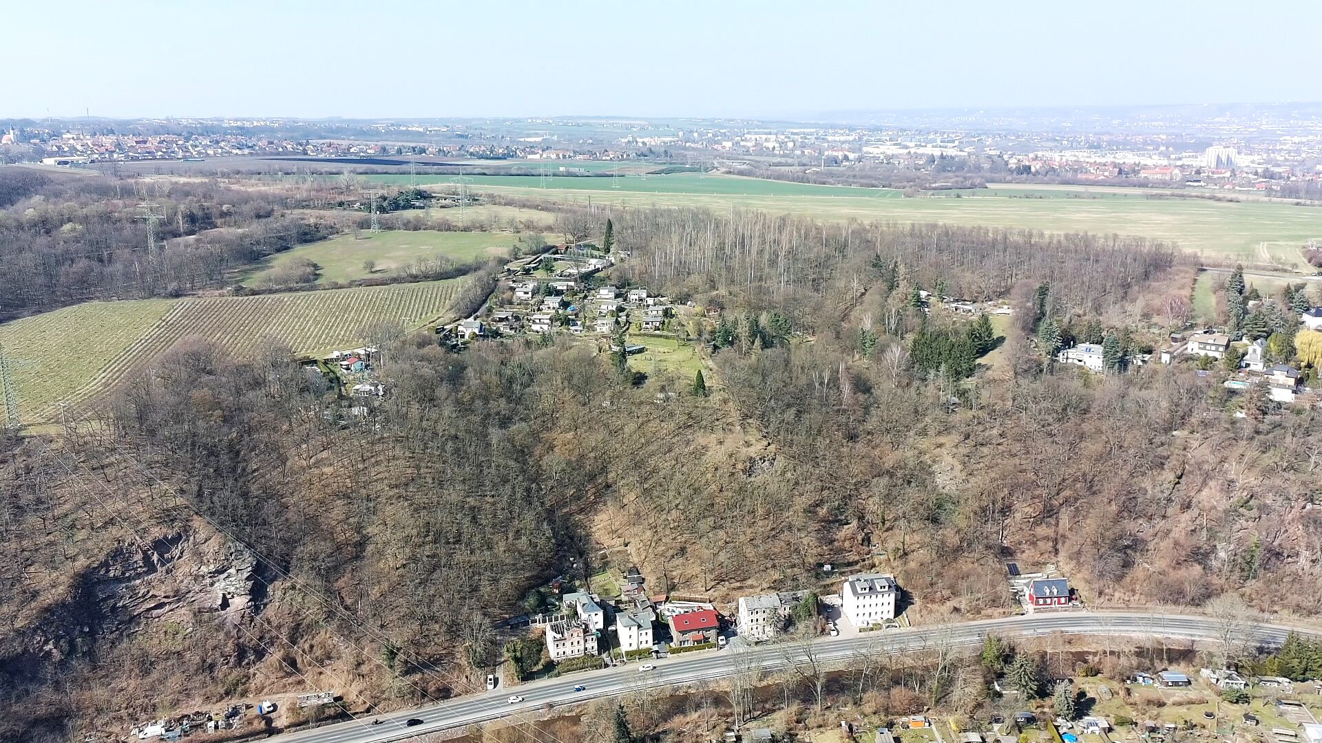 Luftbild über die Talkante hinweg in die weite Dresdner Ebene, unten eine Straße mit Häusern.