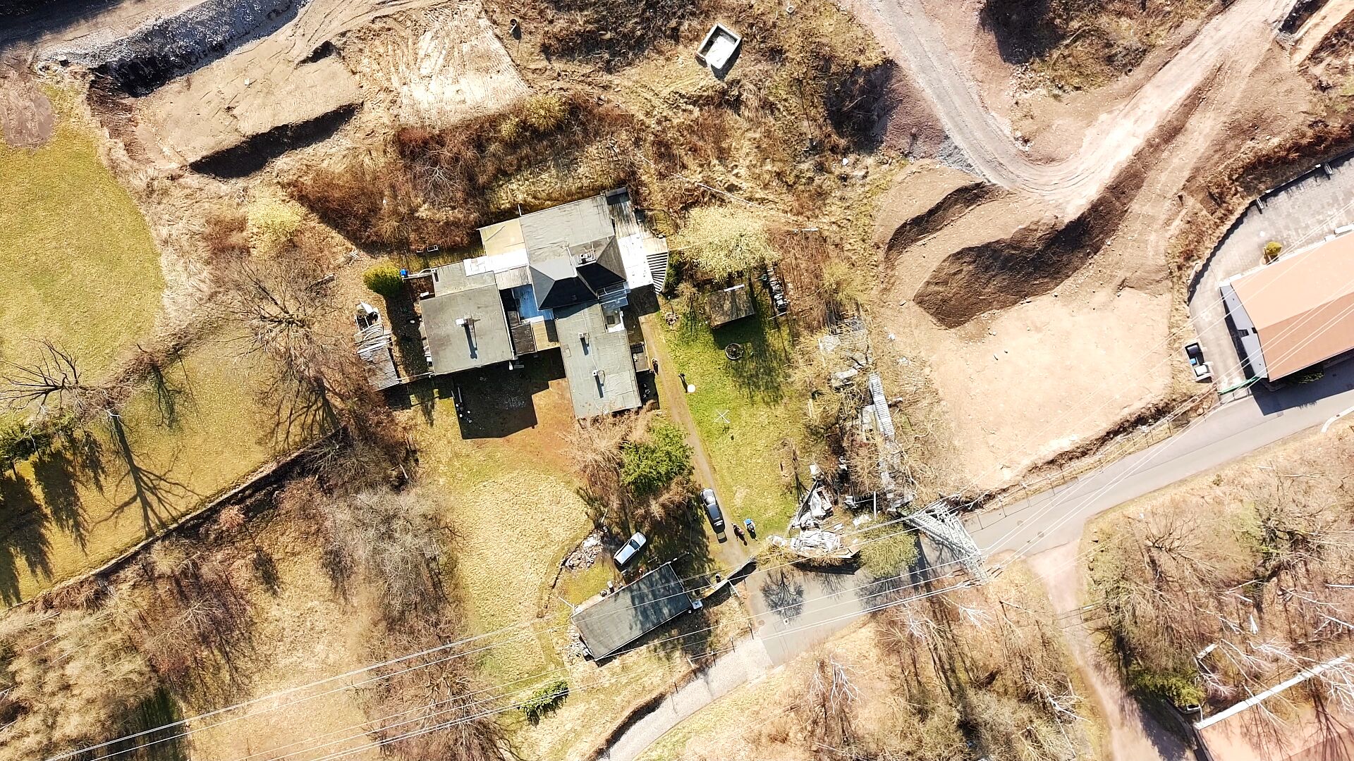 Senkrechte Luftaufnahme des gesamten Anwesens: unten die vier Garagen unter einem Dach, oben der zusammenhängende Baukörper aus Haus 3 mit der Halle, Haus 2 und Haus 1.